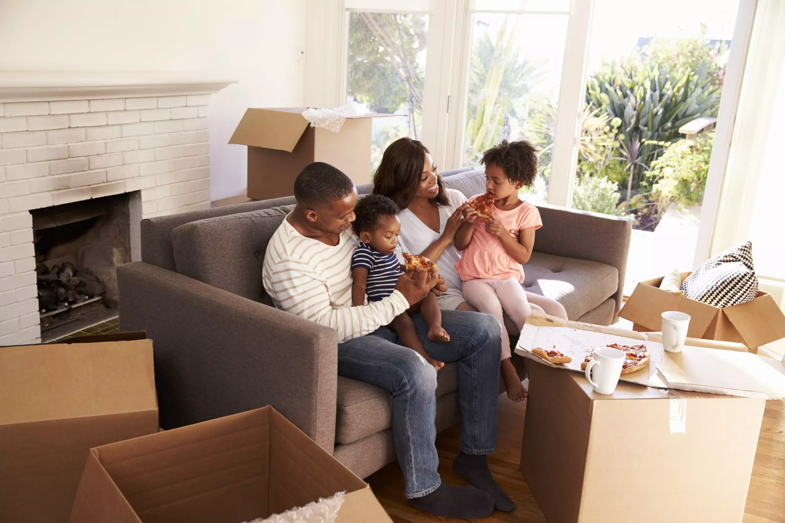 Family Take A Break On Sofa With Pizza On Moving Day