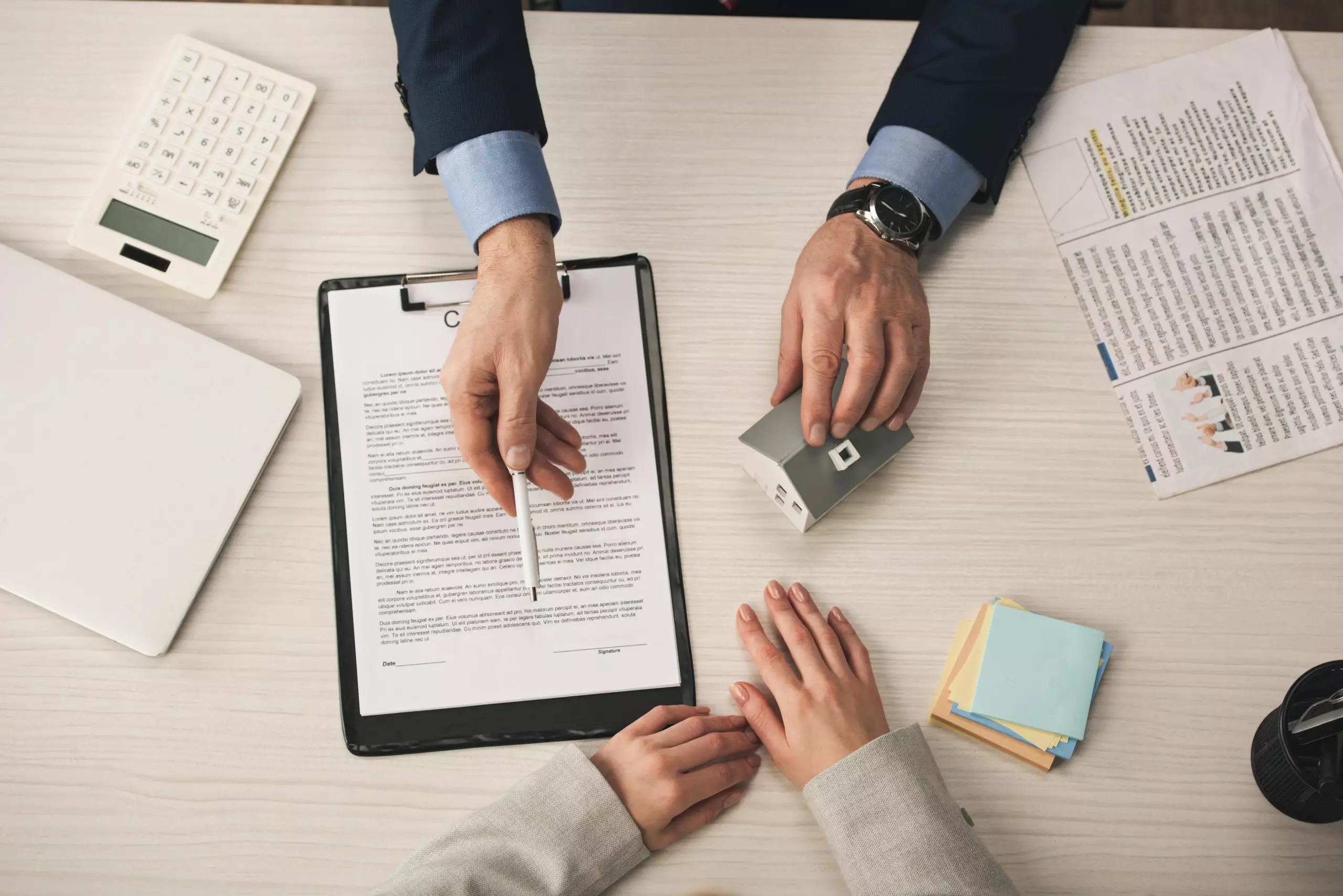 Top view of agent giving pen to woman while touching house model